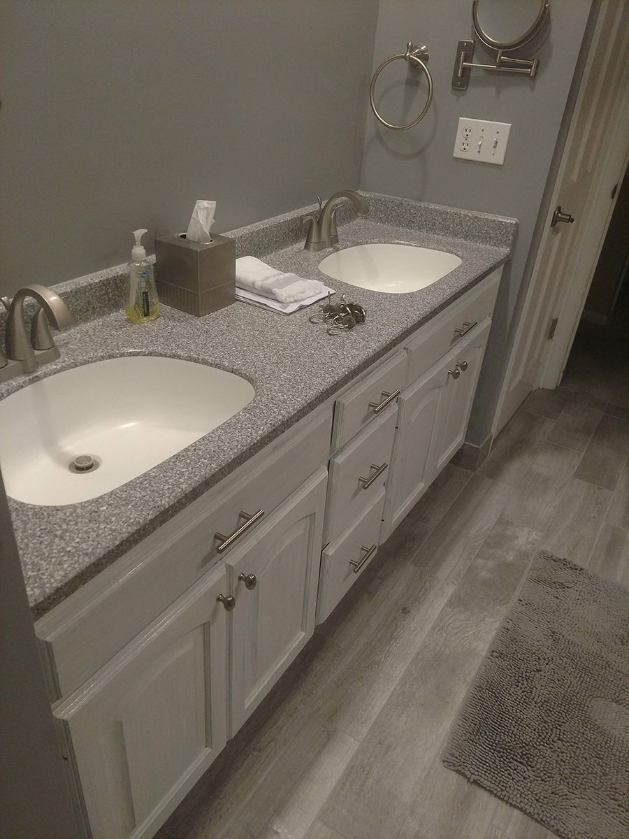 Bathroom vanity with two sinks, gray speckled countertop, white cabinets, and gray walls.