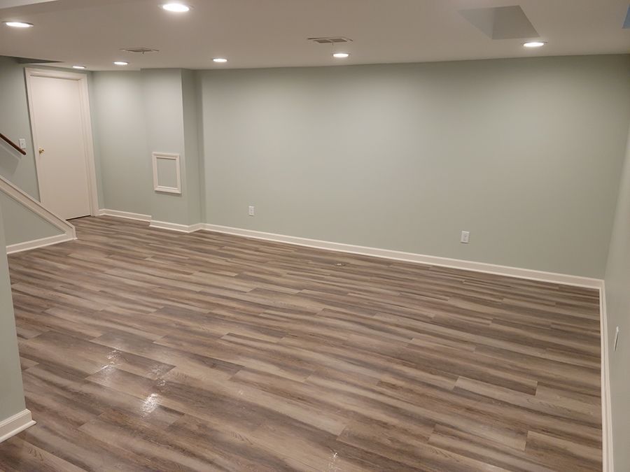 Empty room with light blue walls, wood-look flooring, and recessed lighting.