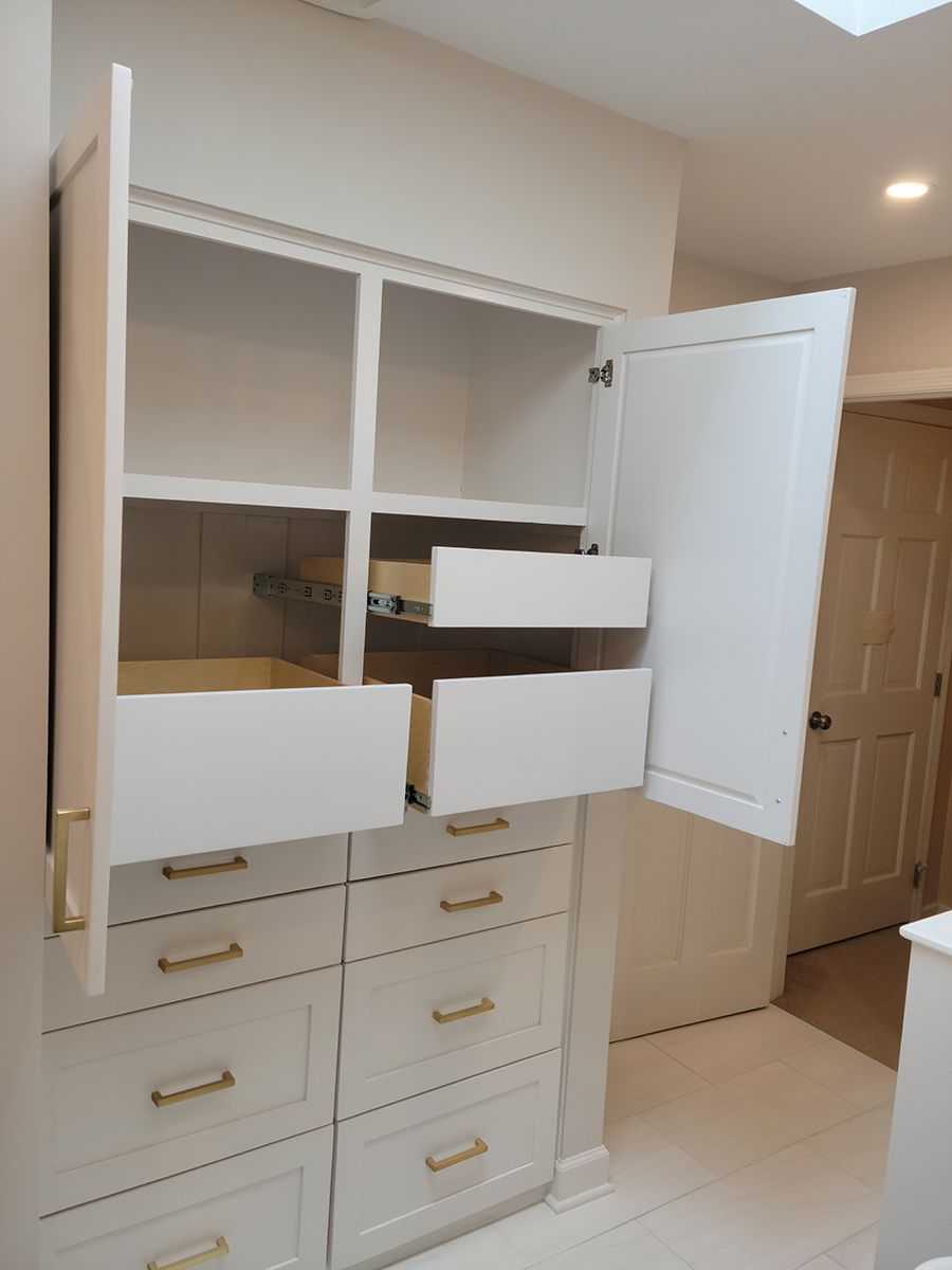 White closet with open doors and drawers, gold handles. Interior view.