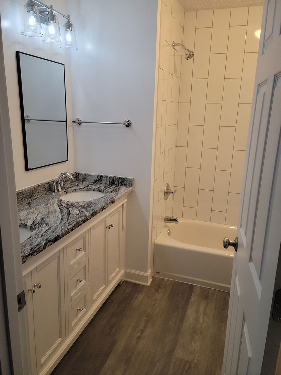 Bathroom interior with white cabinets, gray countertop, and tile shower.
