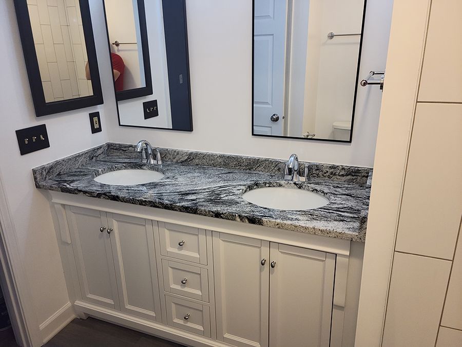 White double vanity with granite countertop, two sinks, and three mirrors.