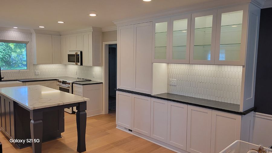 Spacious white kitchen with island, cabinets, countertops, and appliances.