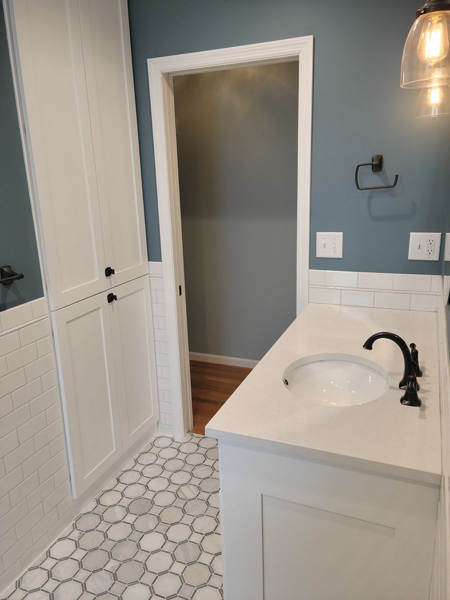 Bathroom with blue walls, white cabinets and countertop, and patterned floor.