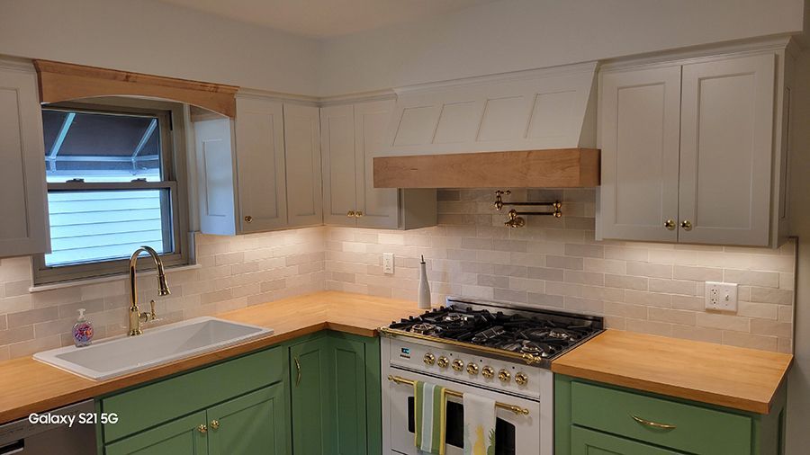Kitchen with green lower cabinets, light upper cabinets, butcher block counters, and a white range.