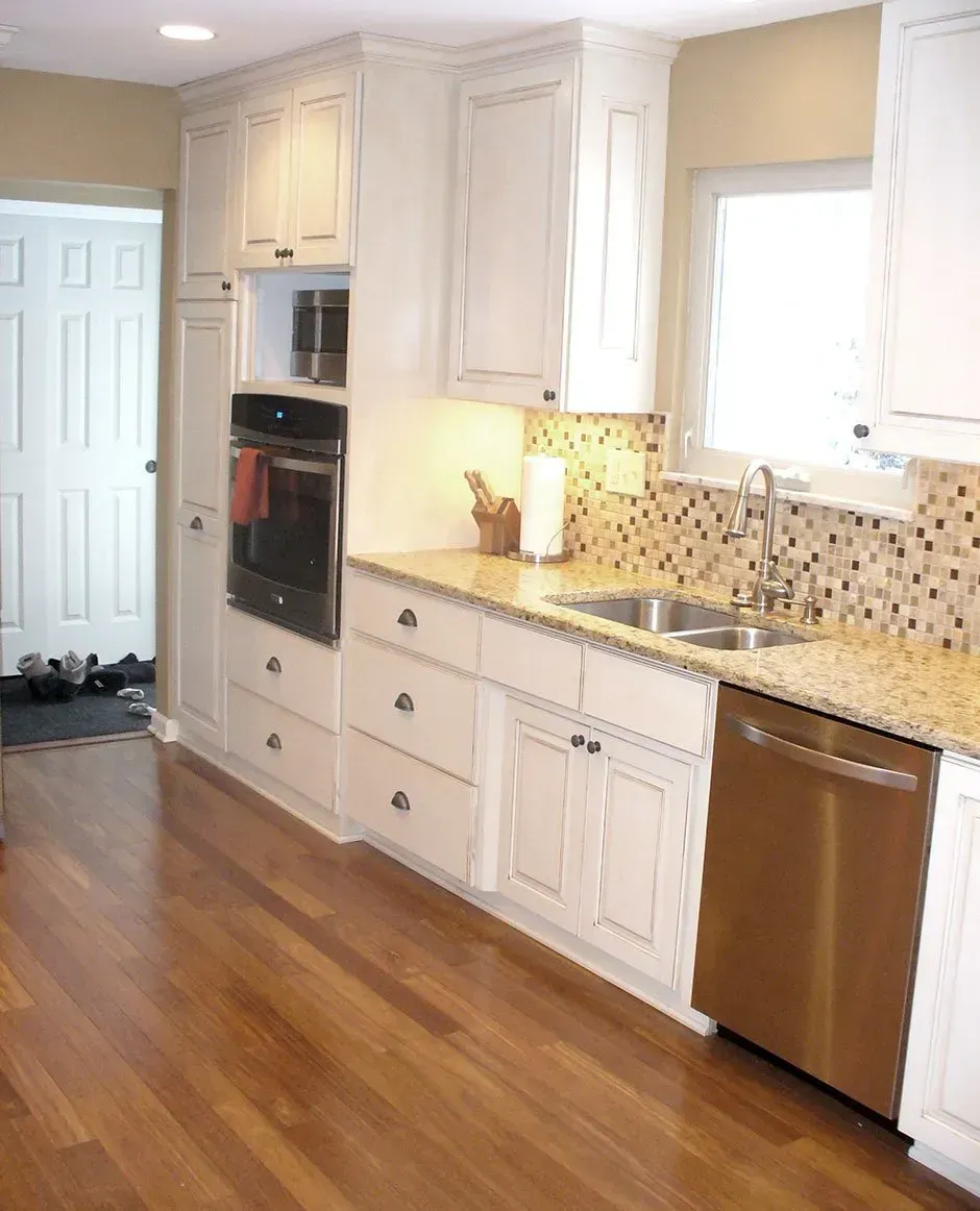 Kitchen with white cabinets, stainless steel appliances, and wood flooring.