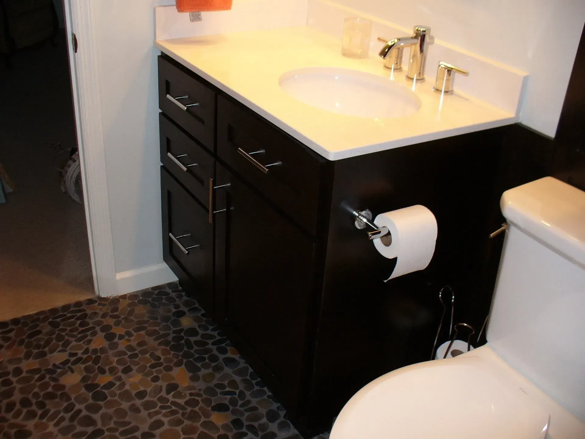 Dark brown vanity with white countertop, round sink, and chrome fixtures in bathroom.