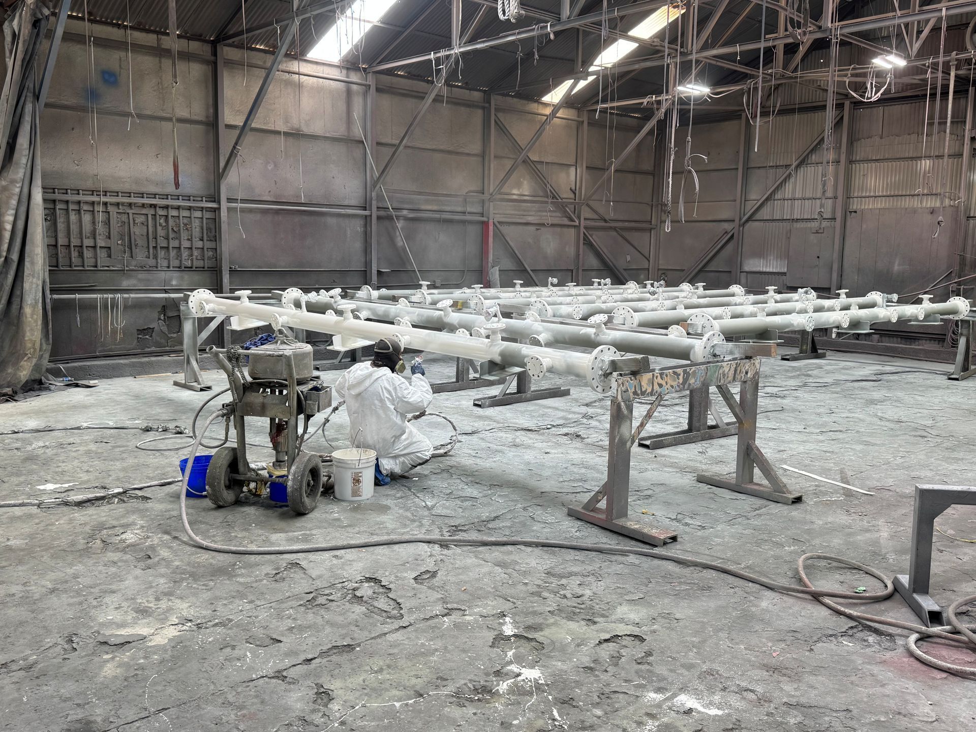 Industrial workshop with a metal frame assembly line and tools on a dusty concrete floor