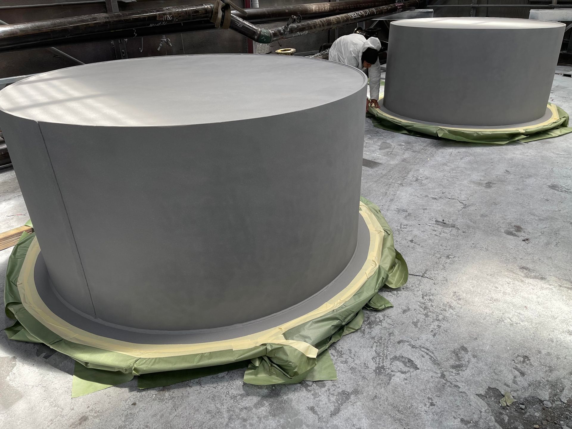 Large gray cylindrical tanks wrapped with green insulation in an industrial setting