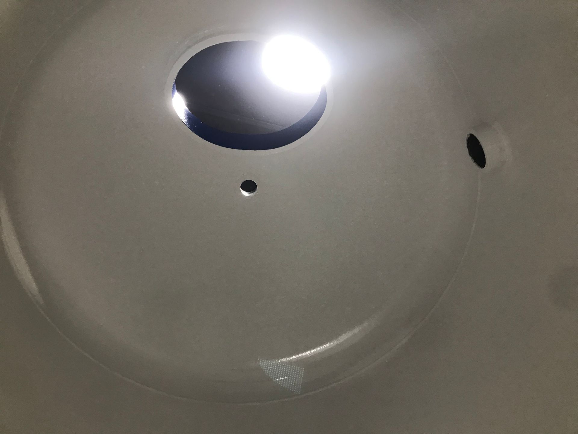 Close-up of a white ceiling light fixture with a bright bulb and dark mounting holes.