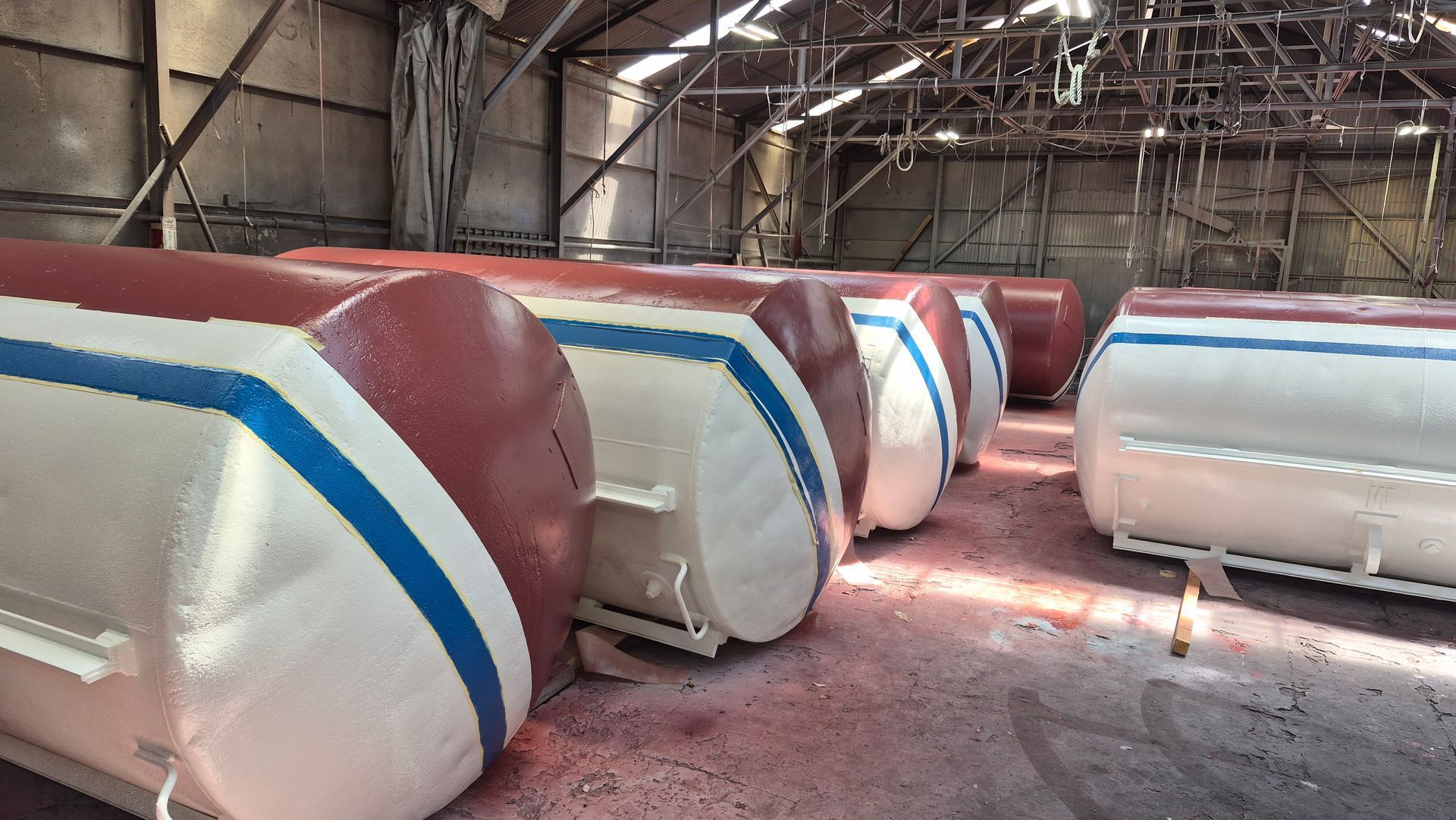 Large red-and-white inflatable structures with blue stripes lined up inside a warehouse.