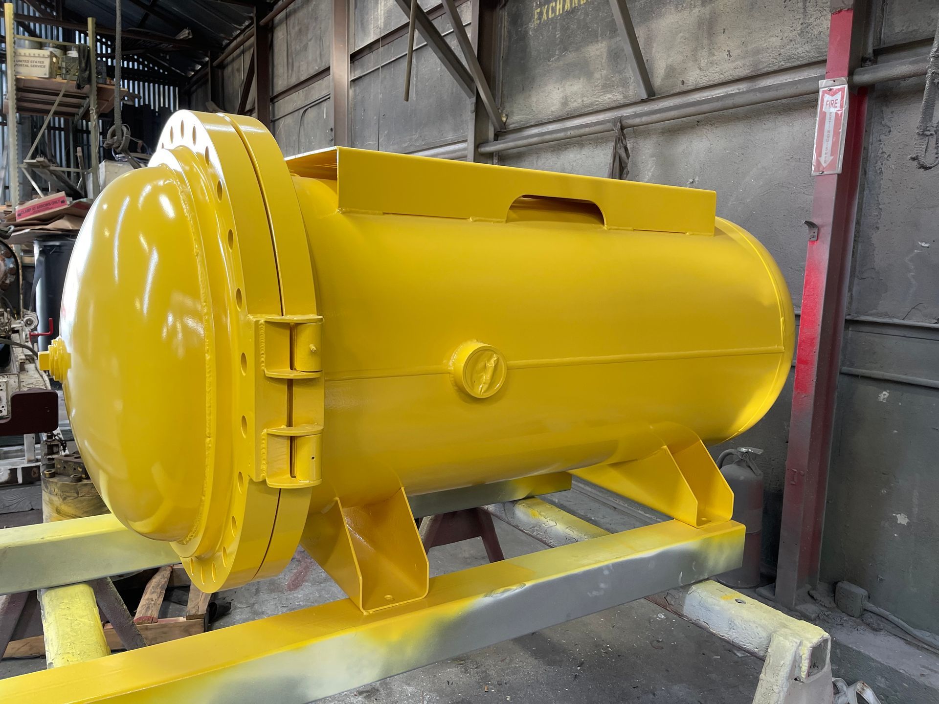 Yellow industrial pressure vessel on a metal frame in a workshop.