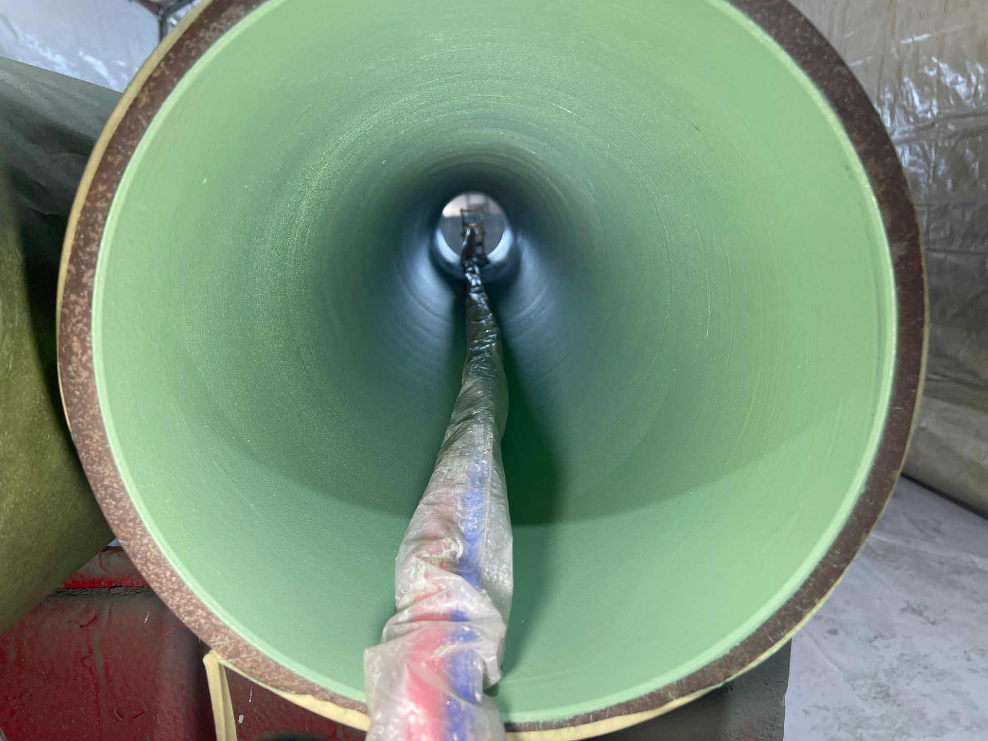 Green pipeline interior with a flexible hose extending into the center