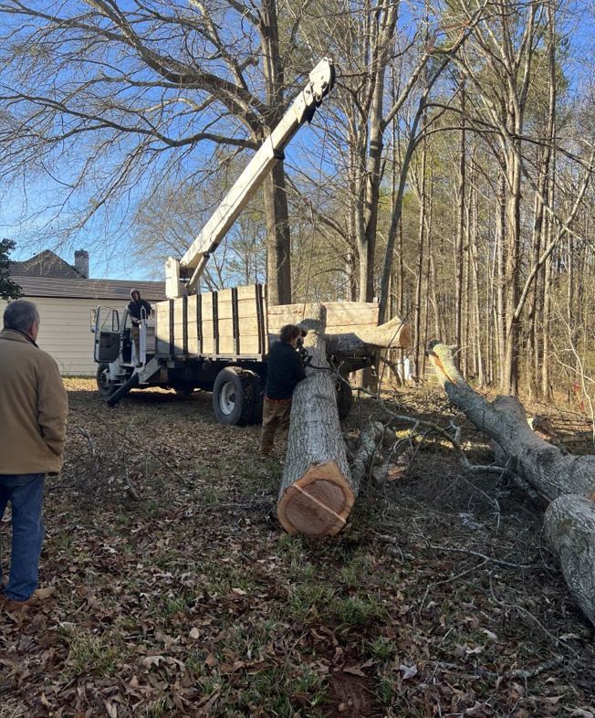 A man is standing next to a truck with a crane attached to it.