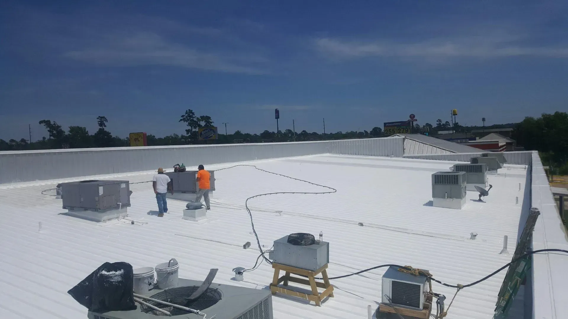 Workers on a white commercial roof. Installing equipment on a sunny day.