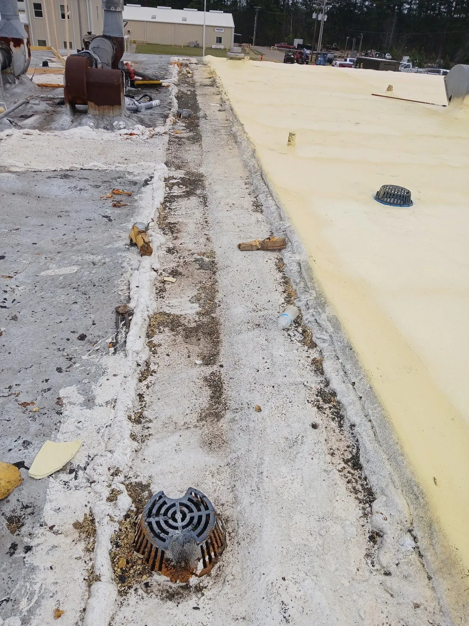 A flat roof with a drain. One side is weathered, the other has fresh yellow foam.