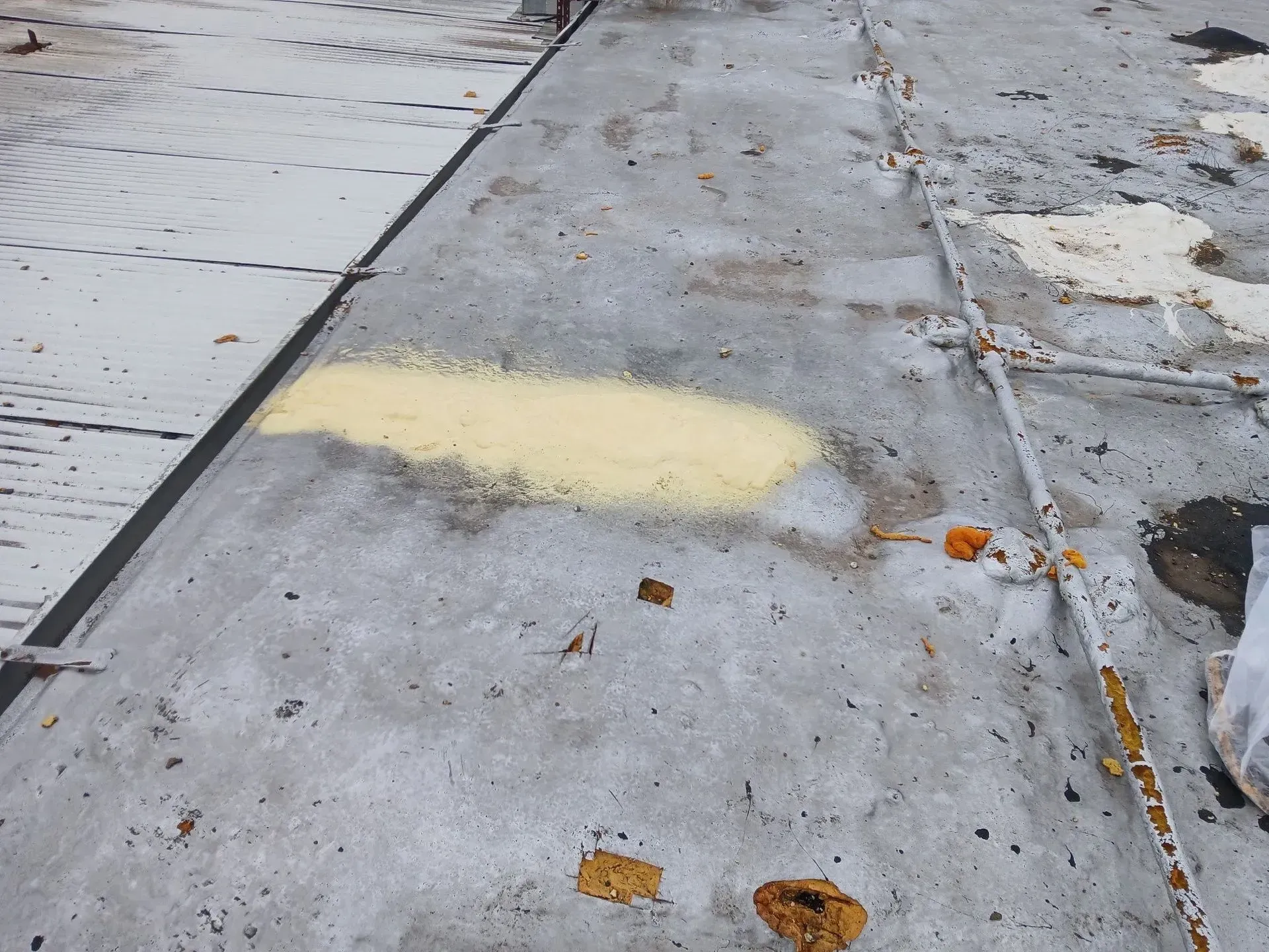 Gray, weathered metal surface with yellow powder splotch and rusty metal strips.