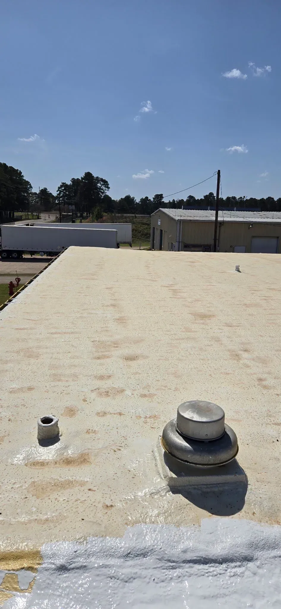 View of a flat roof on a sunny day; two vents are visible.