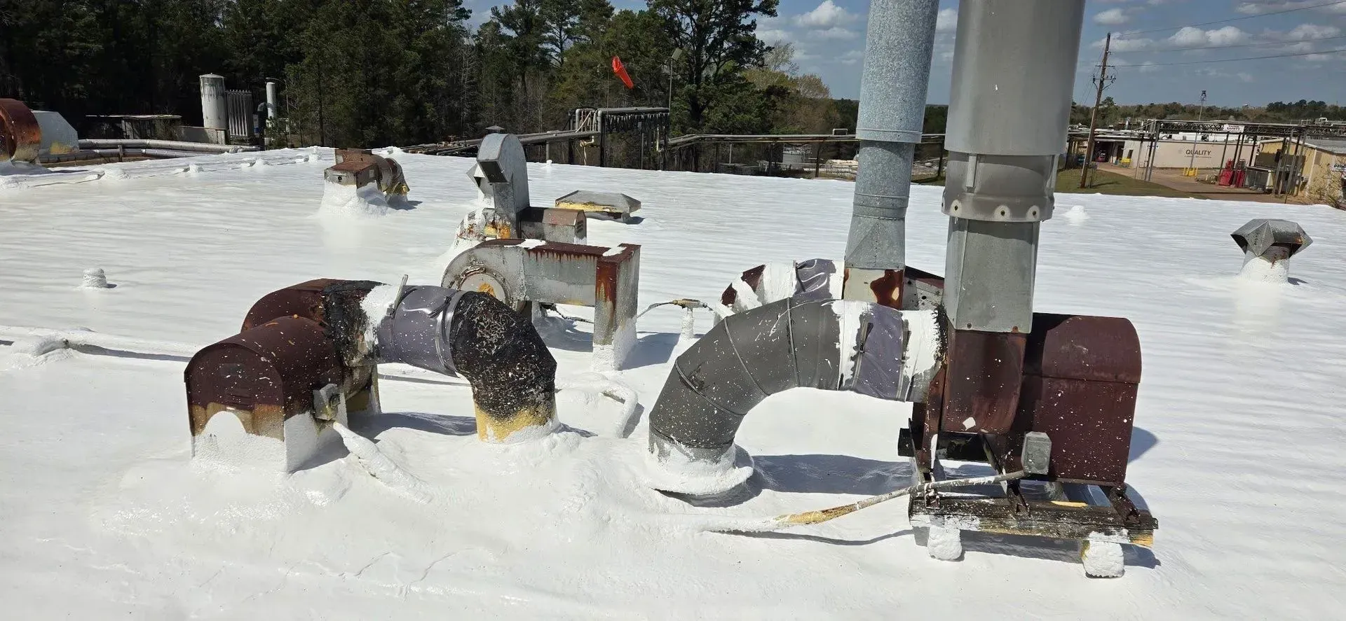Snow-covered rooftop with metal sculptures of dogs and a person's legs and boots.