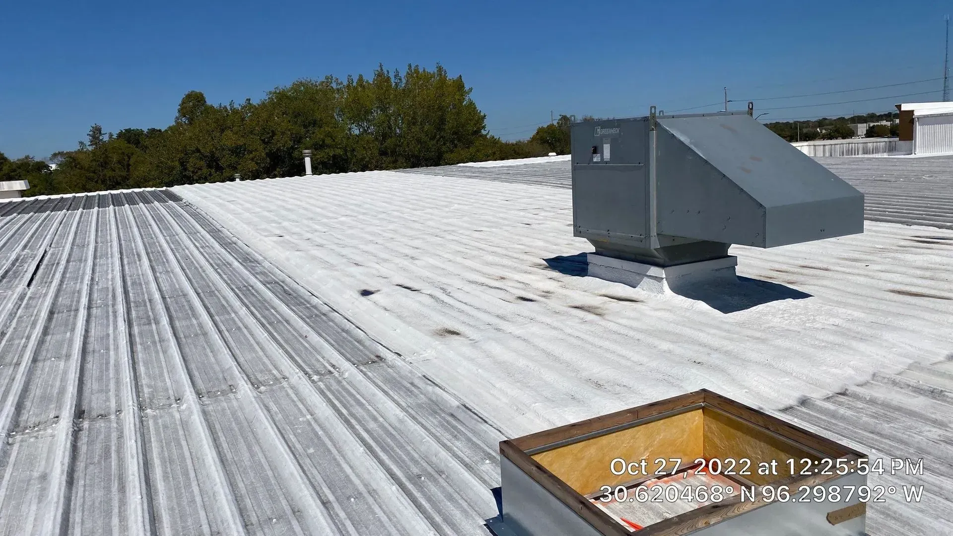 A commercial roof with HVAC equipment; white surface and blue sky in daylight.
