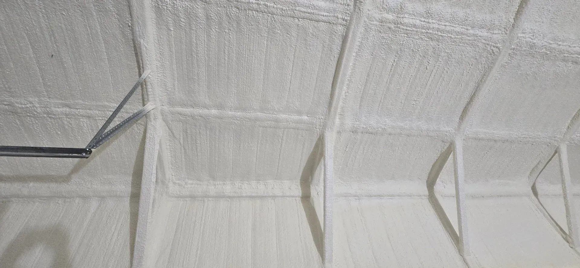 White-painted ceiling with a grid-like structure, possibly a garage or unfinished room, with lines and beams.
