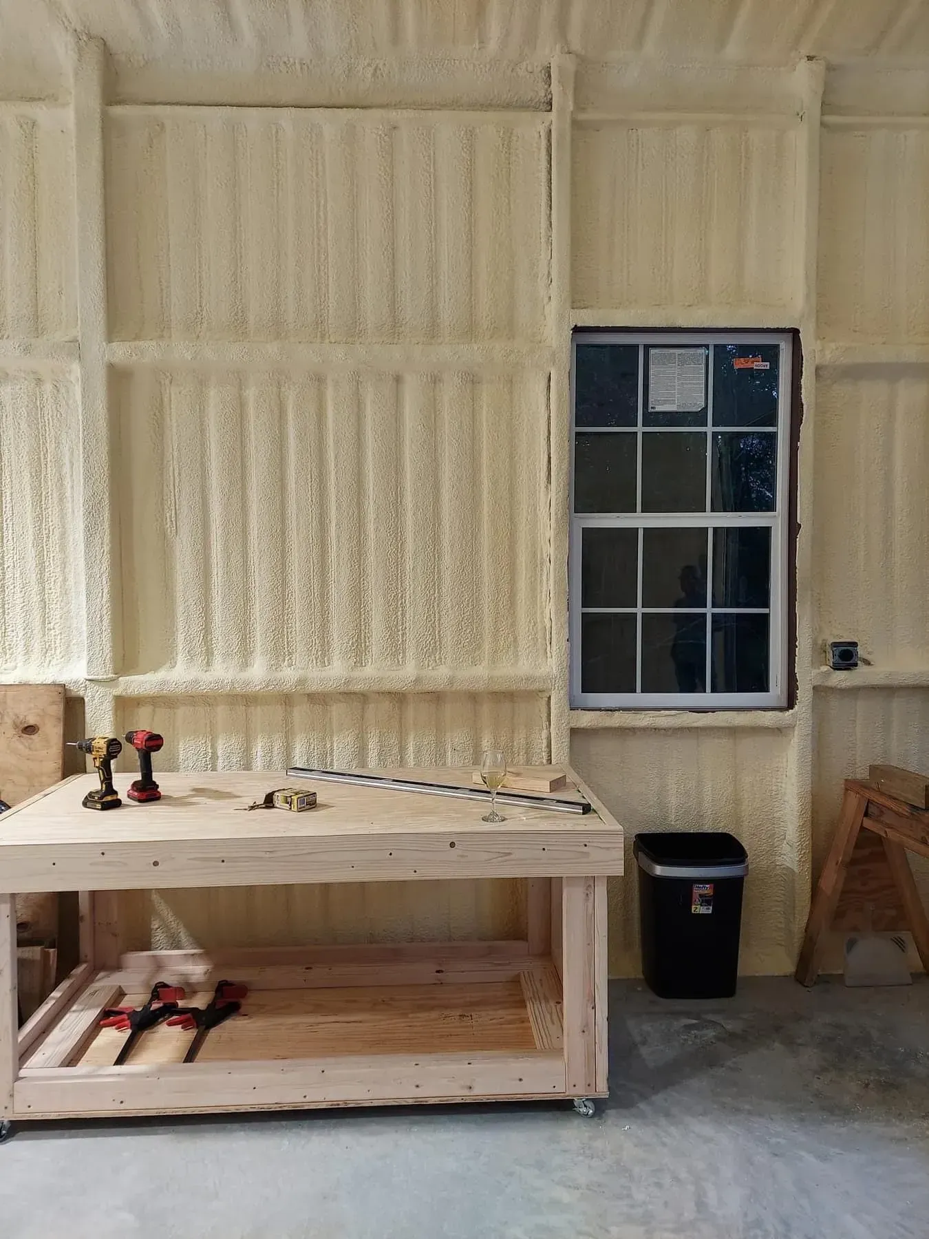 Garage interior with spray foam insulation, a workbench, and a window.