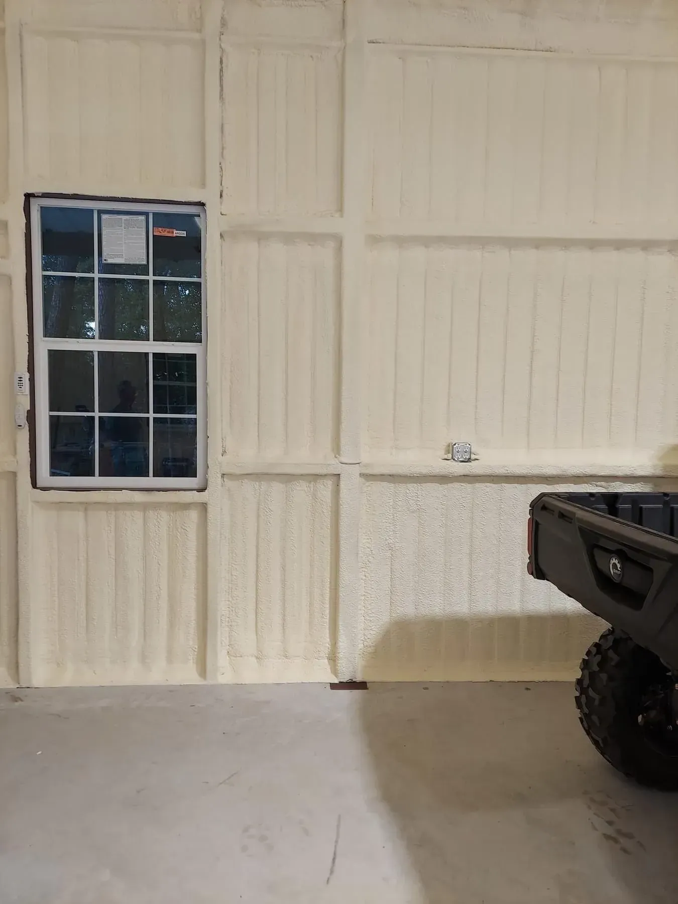 Interior of a building with insulated walls, a window, and a utility vehicle.