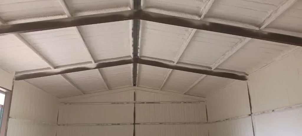 Interior view of a building with a vaulted ceiling and exposed support beams. The walls and ceiling are painted white.