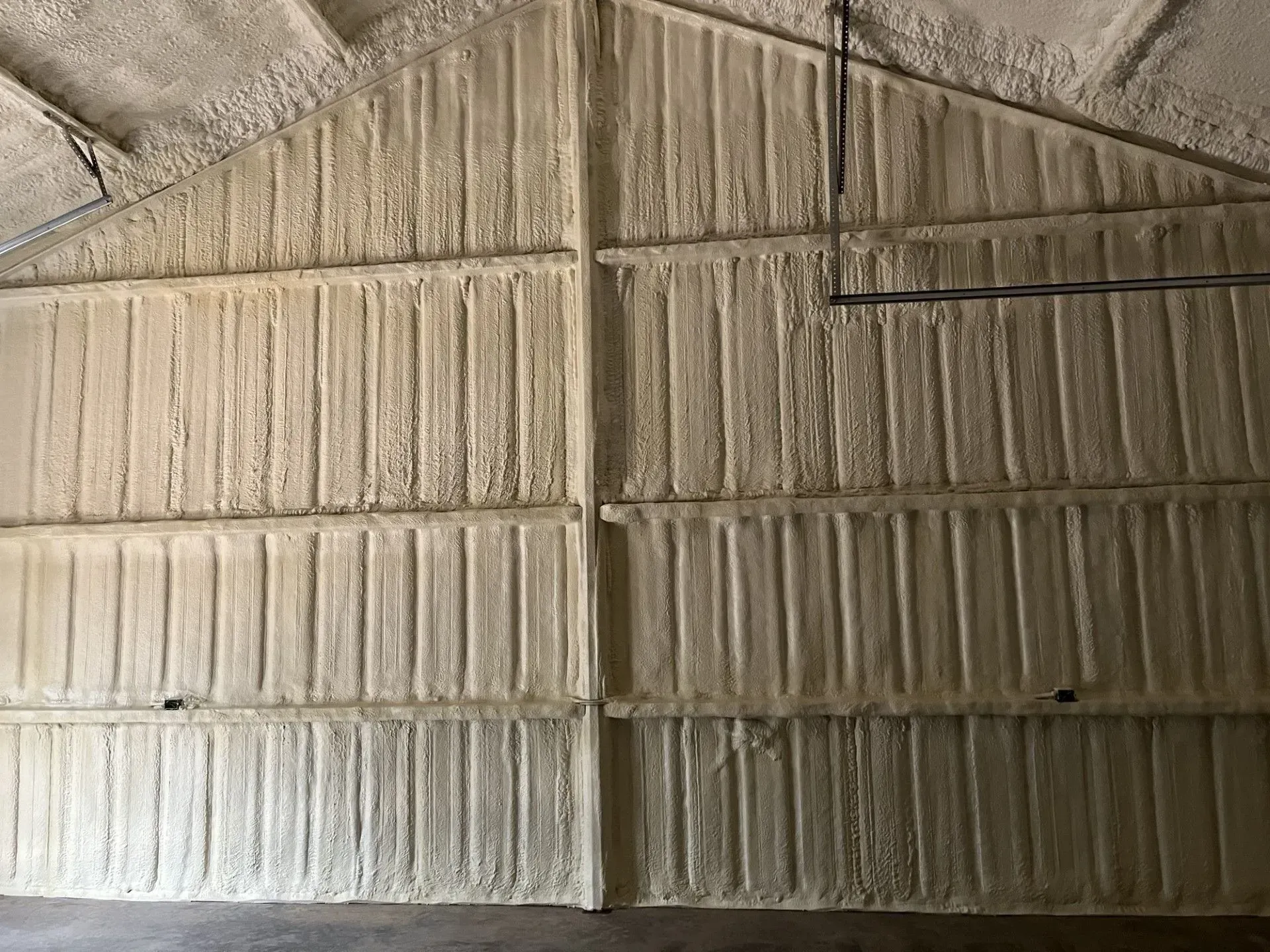 Interior of a building with walls and ceiling insulated with tan spray foam.