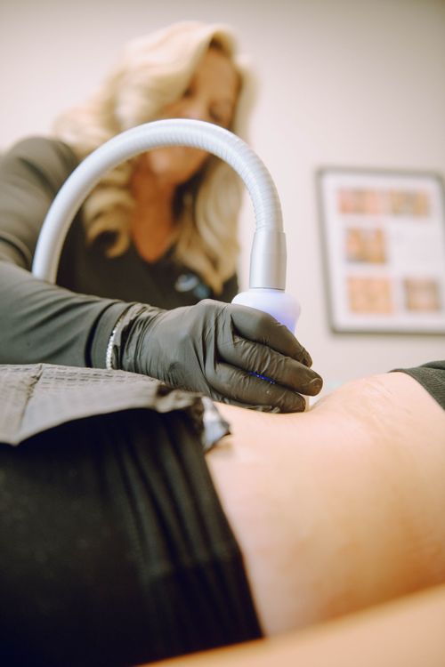 A professional administering a body contouring treatment with a device on a person's abdomen.