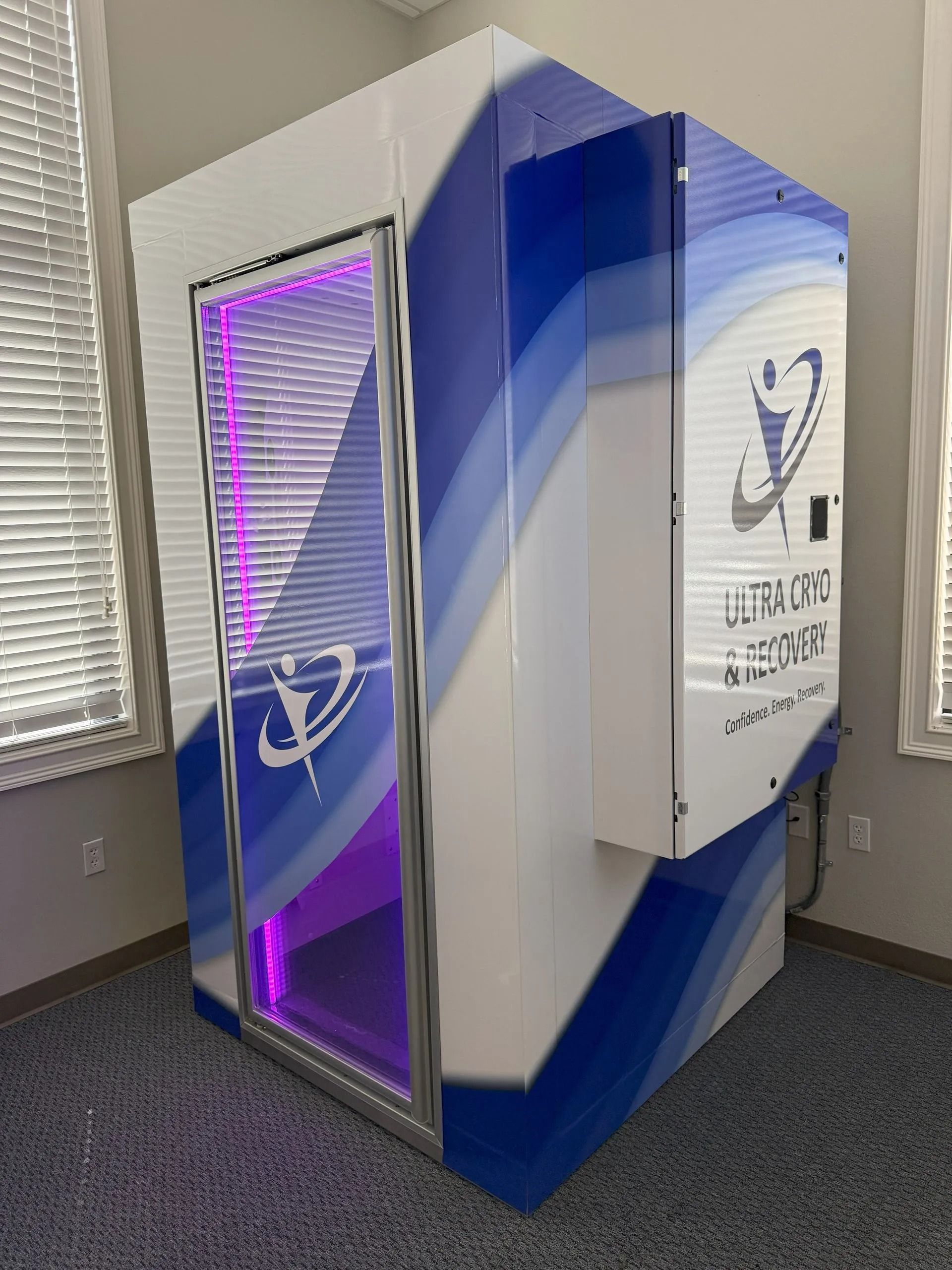 Cryotherapy chamber, white and blue with purple interior lighting, in a room with a window.