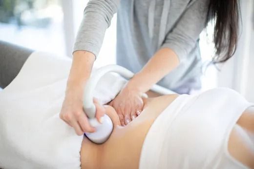 Person receiving abdomen treatment with a handheld device, in a light-filled setting.