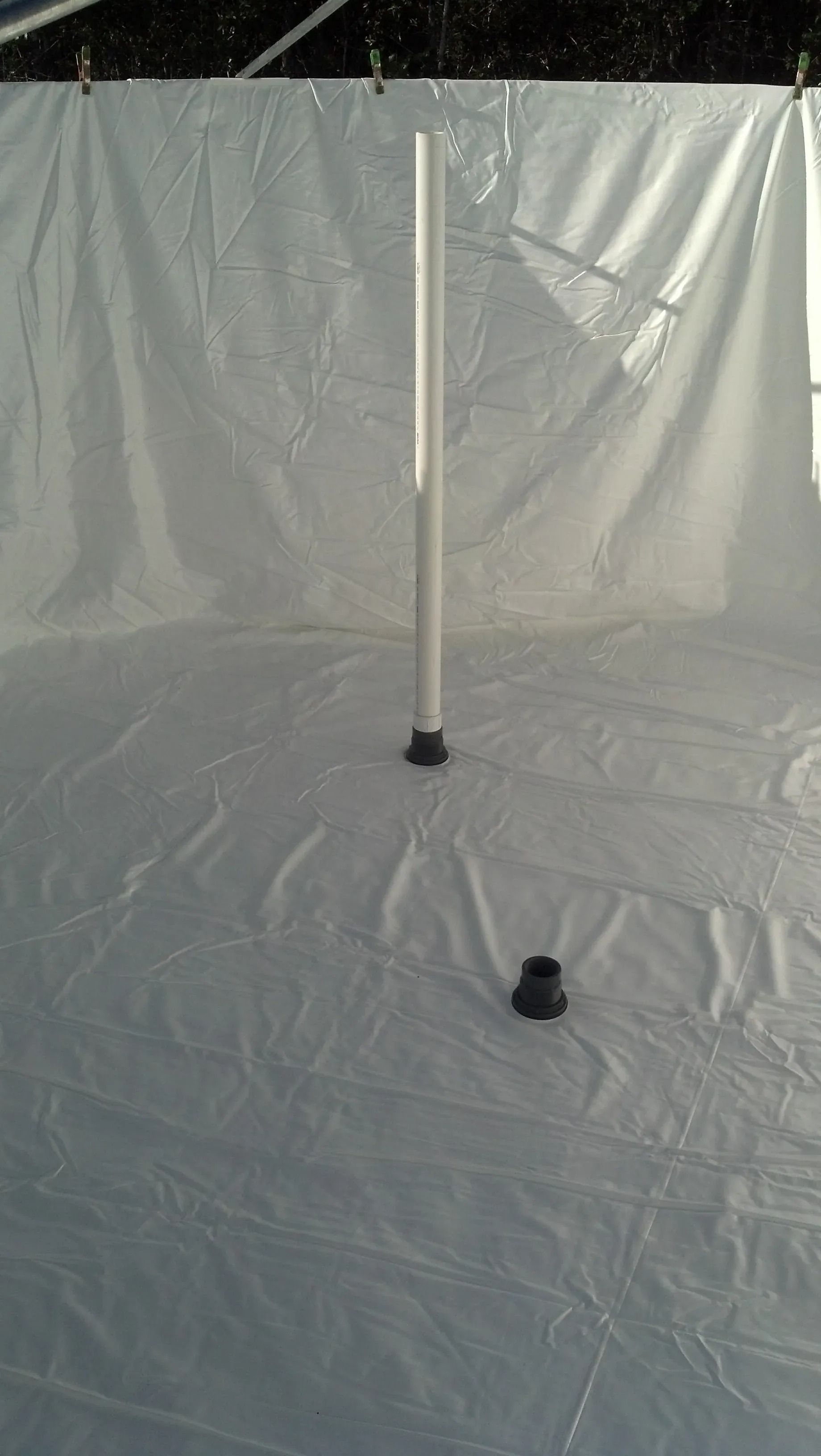 White pole on a plastic-covered floor with a black base in a tent-like setup