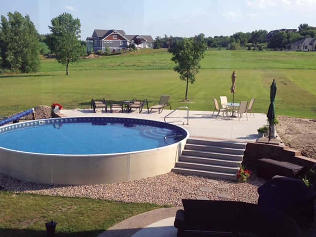Backyard with round swimming pool, patio seating, and green lawn in a suburban setting