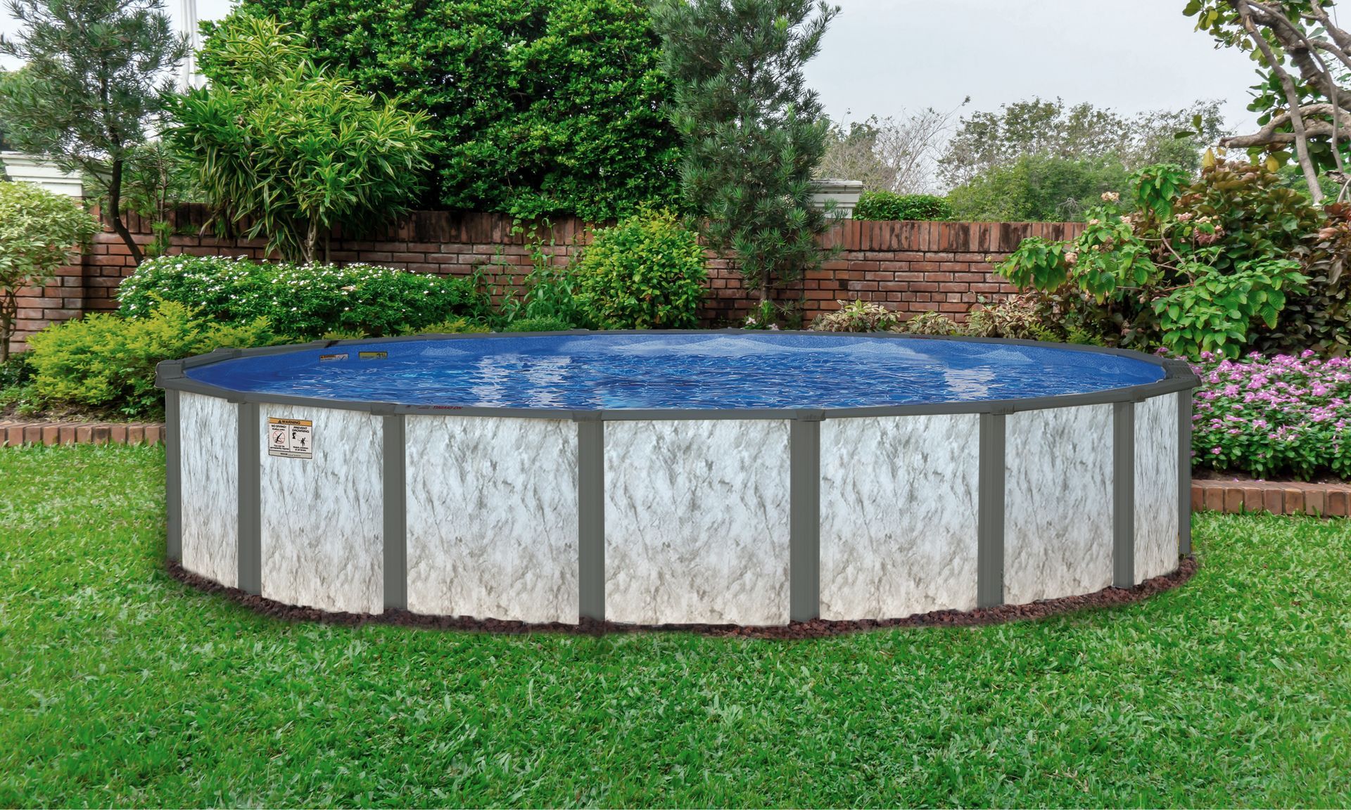 Round above-ground pool in a grassy backyard with trees and a brick wall
