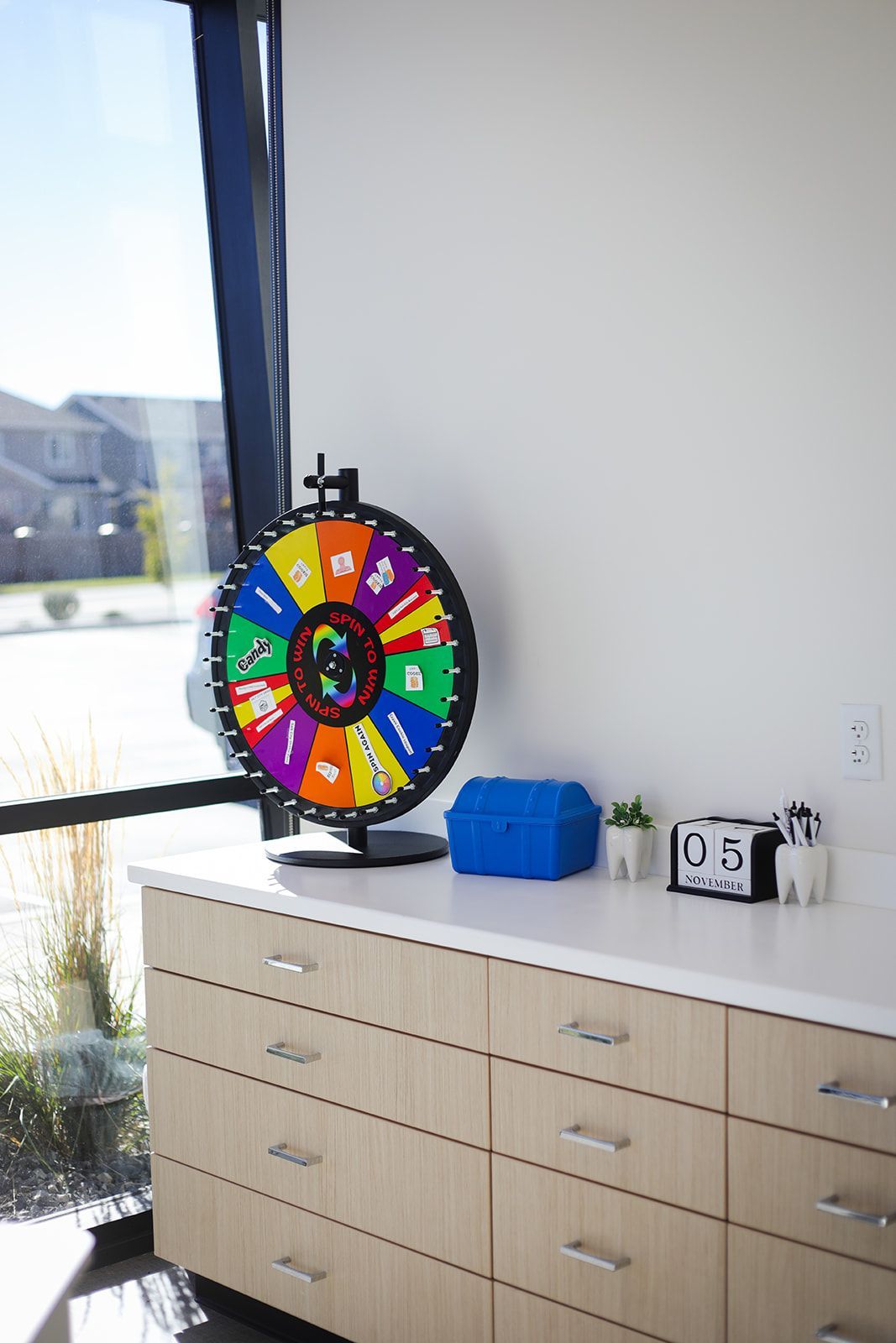 A spinning wheel is sitting on top of a counter next to a window.