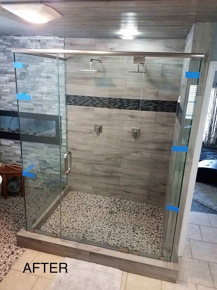 A bathroom with a walk in shower with sliding glass doors
