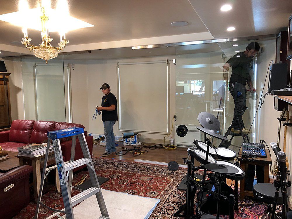 A man is standing on a ladder in a living room next to a drum set