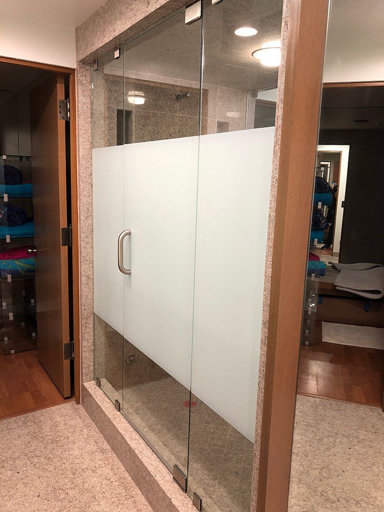 A bathroom with a glass shower door with frosted glass