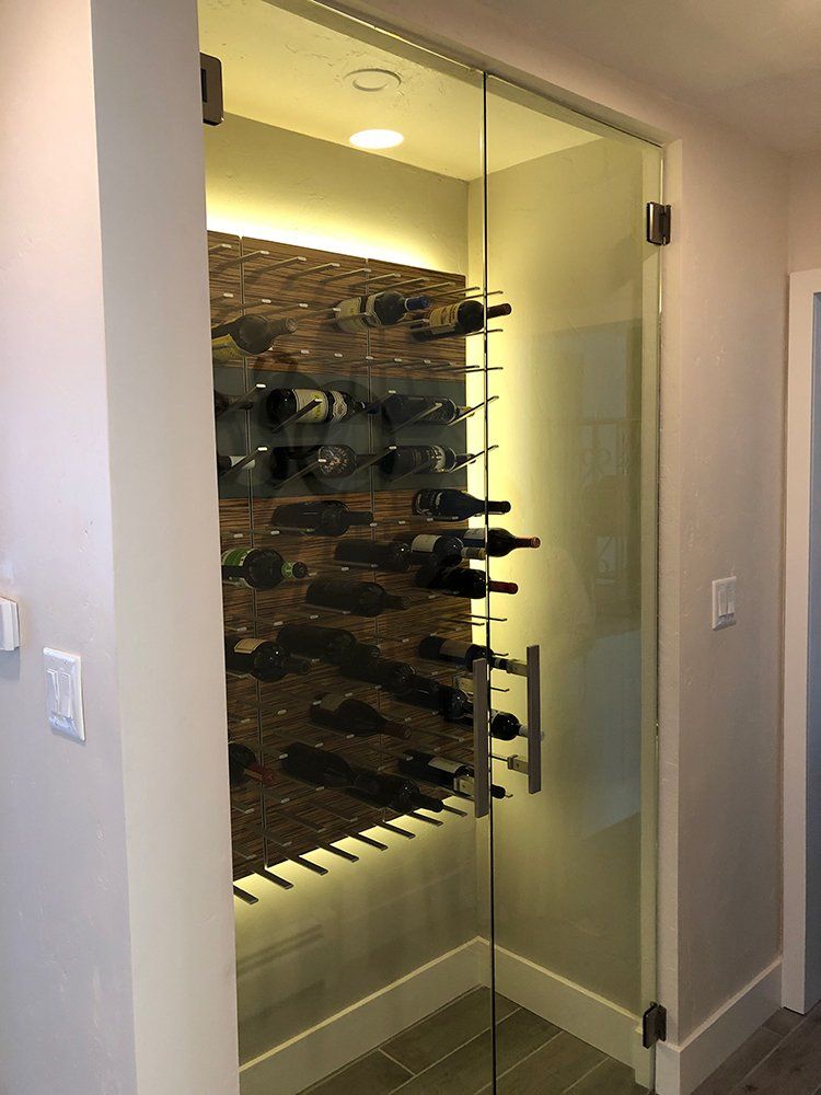 A wine cellar with a glass door and a wine rack filled with wine bottles