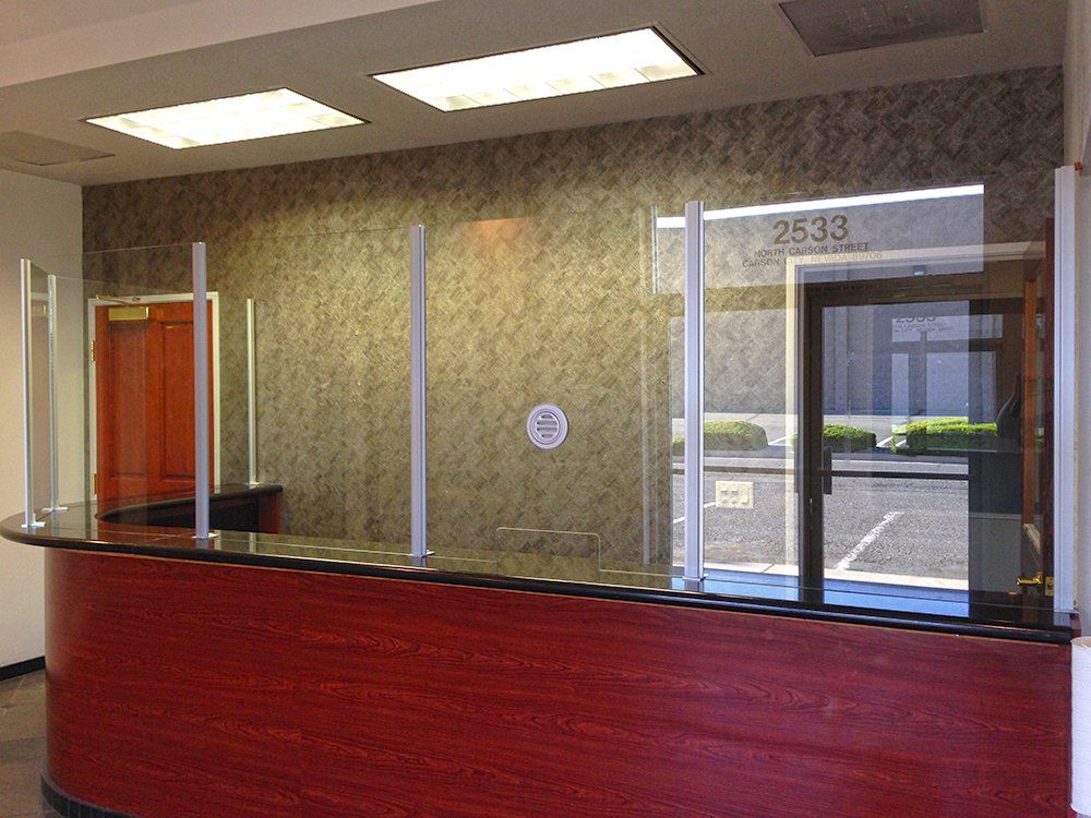 A reception desk with a glass barrier between it and a window