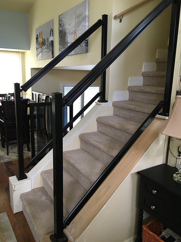 A set of stairs with a black railing in a living room