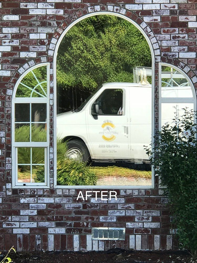 A white van is reflected in the window of a brick building
