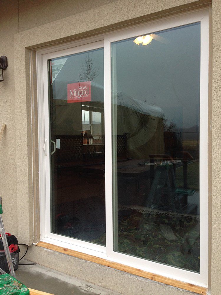 A white sliding glass door is sitting on the side of a building