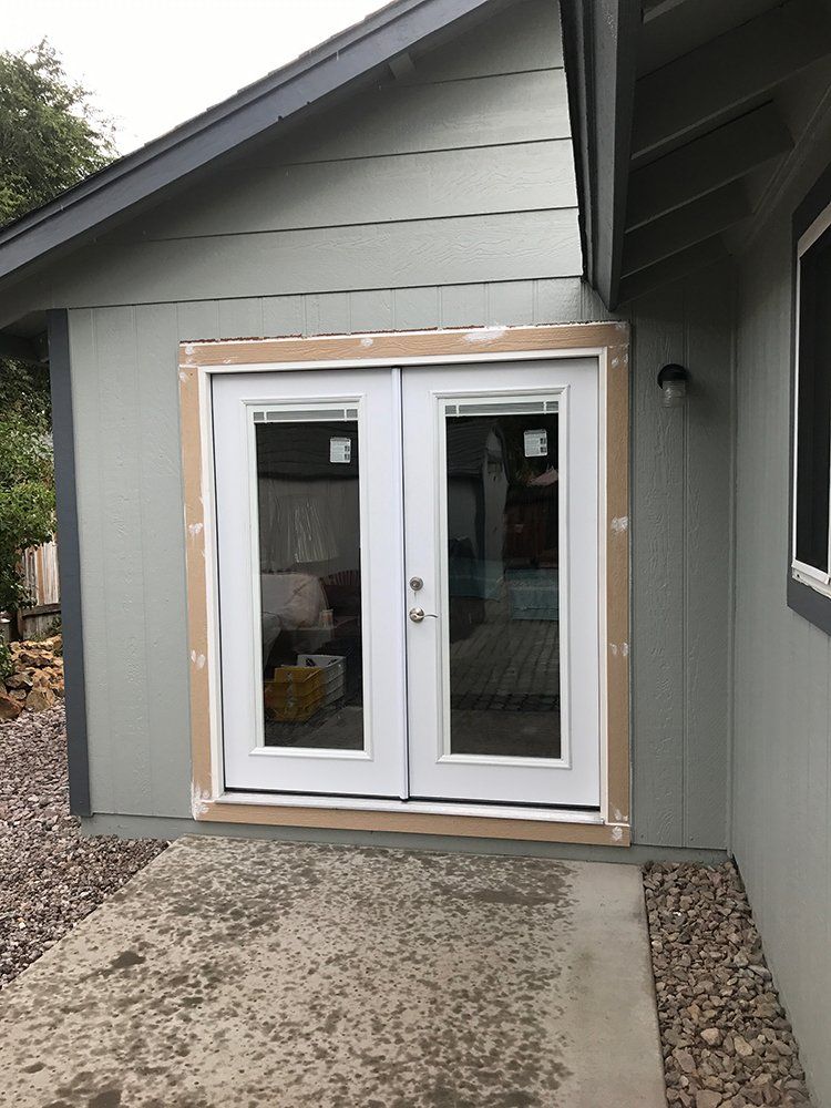 A white patio door is being installed on the side of a house