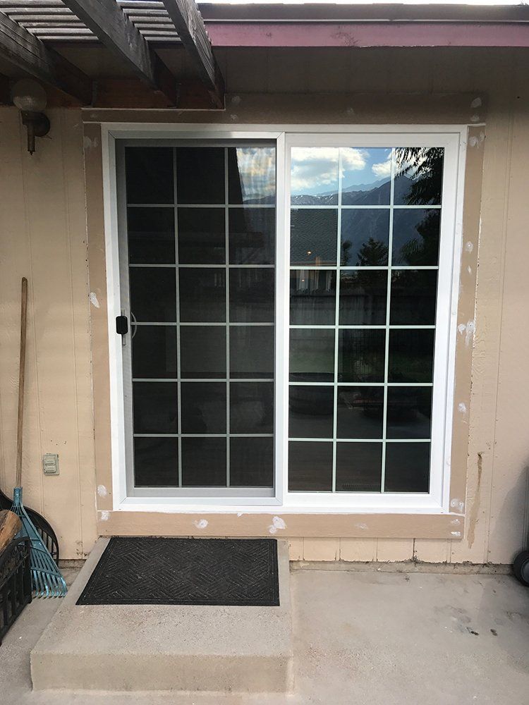 A sliding glass door with a black mat in front of it