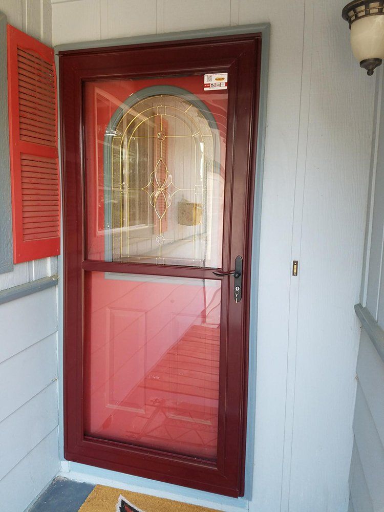 A red door with a glass window is on a porch