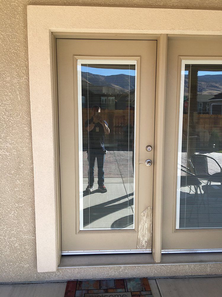 A person is standing in front of a door with blinds on it