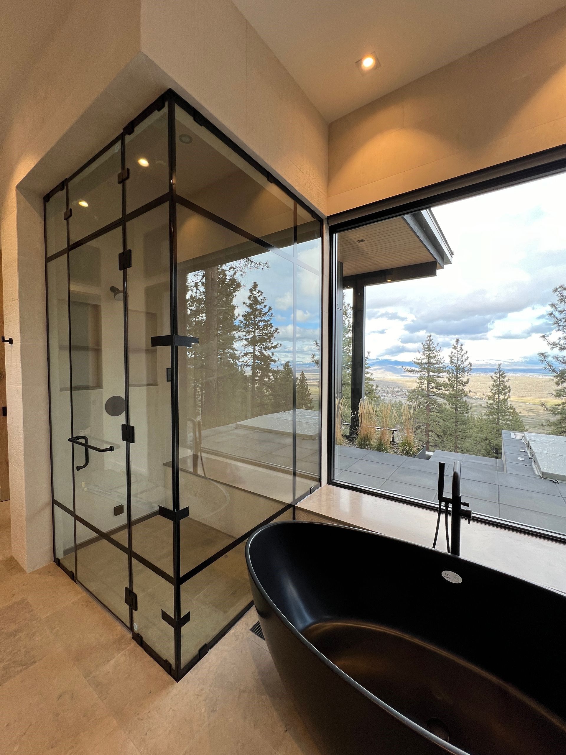 A bathroom with a black bathtub and a glass shower
