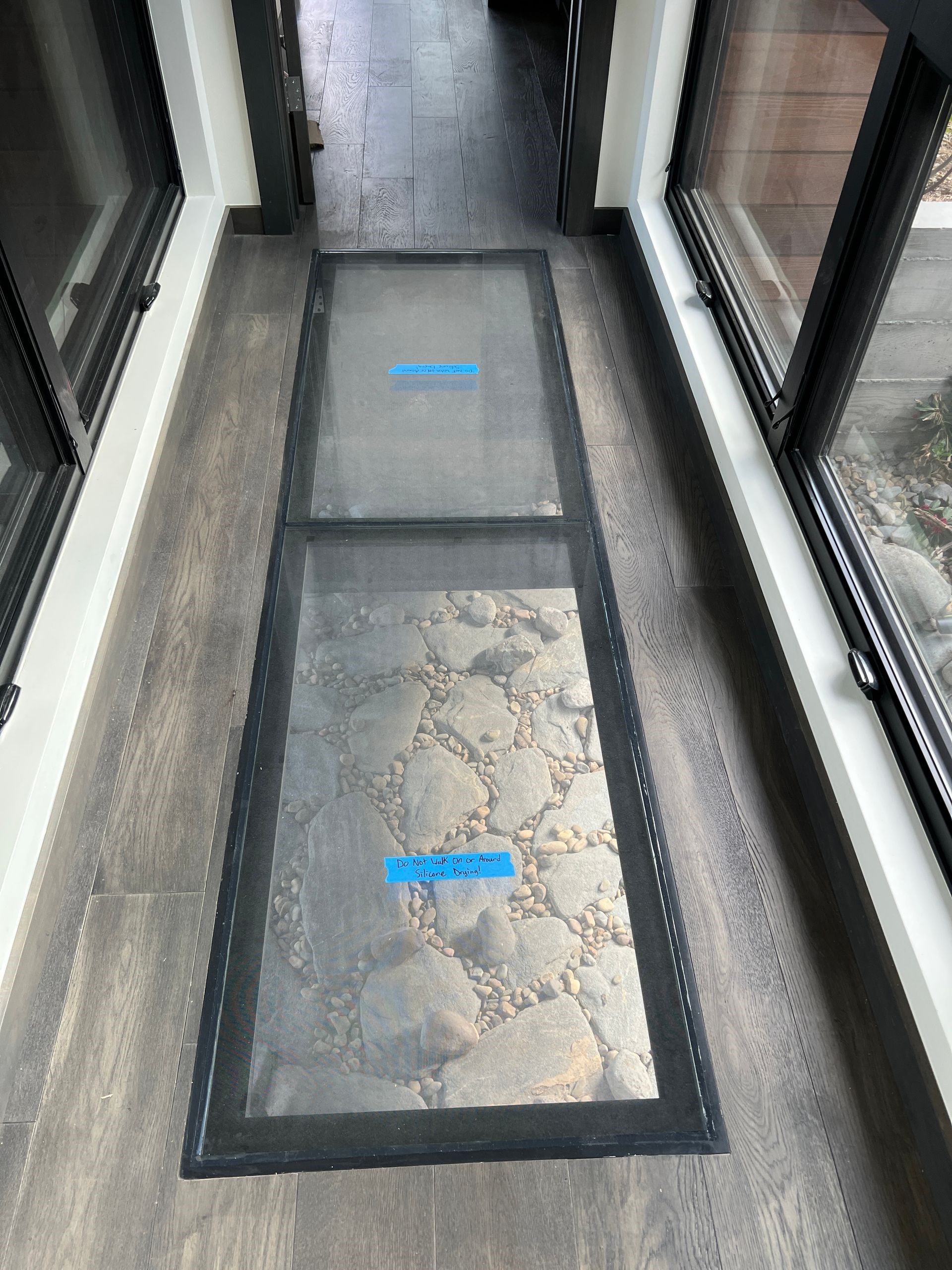 A hallway with a glass floor and a sliding glass door