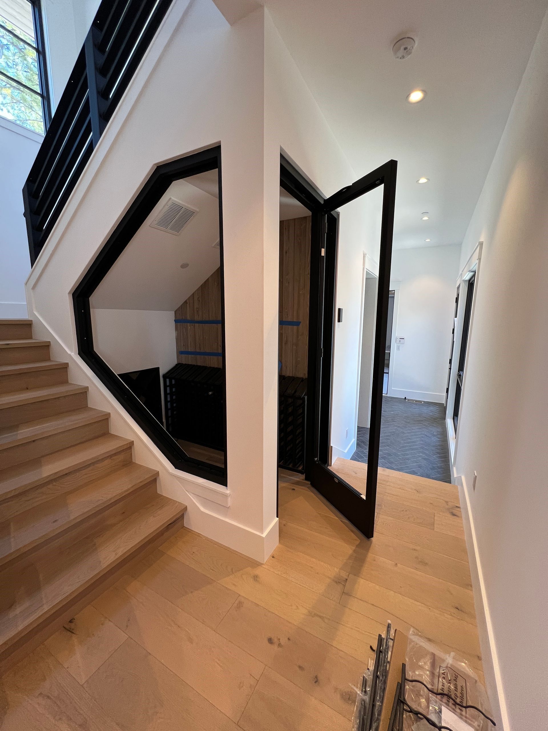 A hallway with stairs and a glass door that is open